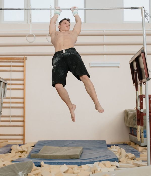 Athletic man performing a bodyweight strength exercise in a dark gym.